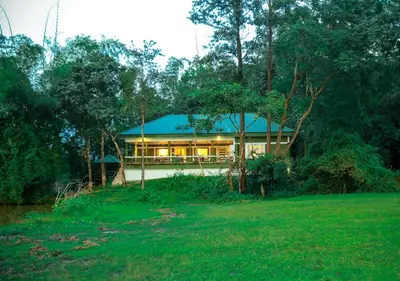 a house with a blue roof in the forest at Tusker Inn Forest Lodge in Pulpally
