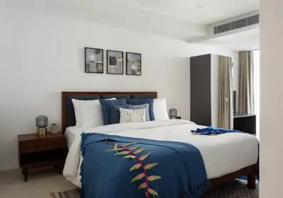 a bedroom with a large bed with a blue blanket at Quad One in Kozhikode