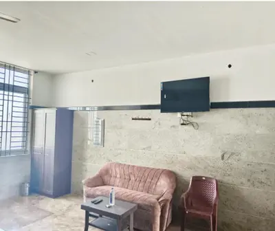 a living room with a couch and a tv on a wall at Prm classic lodge in Erode