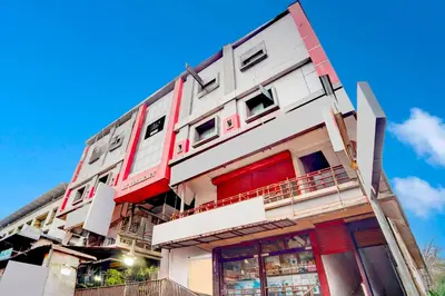 a tall white building with red doors and windows at Collection O Kunnamangalam Near Bus Stand in Kunnamangalam