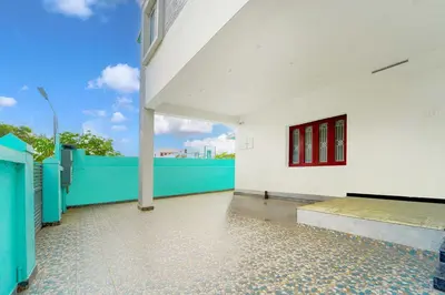 a white building with red windows and a blue fence at Collection O Ganapathy Athipalayam Pirivu Road in Coimbatore