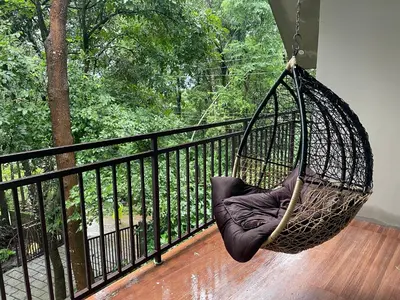 a hanging hammock on a balcony with a tree at Aambal Wayanad Pool House Resort by Veda Retreat in Wayanad