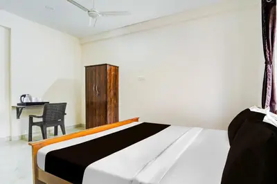 a bedroom with a bed and a chair and a table at Super Collection O RS Puram North Railway Station Formerly RG Residency in Coimbatore