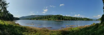 a view of a river with trees in the distance at Vipinam, The riverside retreat in Kotamangalam