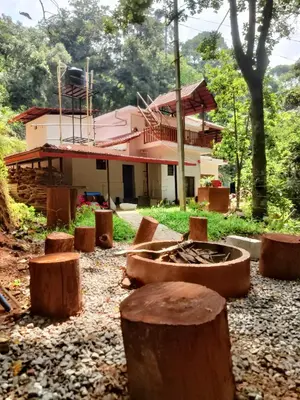 a house with a bunch of logs in front of it at Reevilla in Madikeri