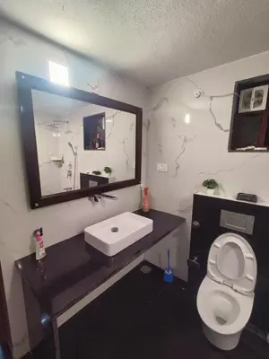 a bathroom with a sink and a toilet and a mirror at Reevilla in Madikeri