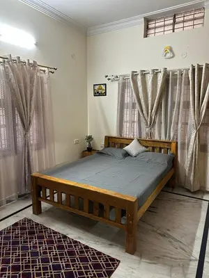 a bedroom with a wooden bed in a room with curtains at Raaha Luxury Home Stay in Mysore