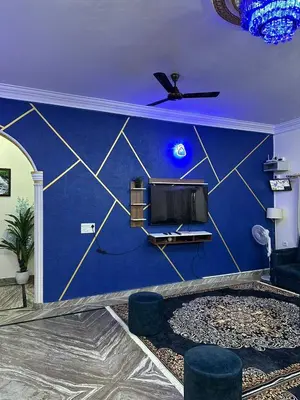 a living room with a blue wall with a tv at Raaha Luxury Home Stay in Mysore