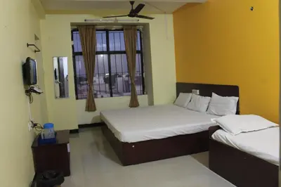 a bedroom with two beds and a tv and a window at Aishvarya Residency in Coimbatore