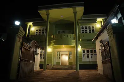 an empty house at night with a gate at Dormer Stay in Kozhikode