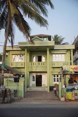 a yellow house with a palm tree in front of it at Dormer Stay in Kozhikode