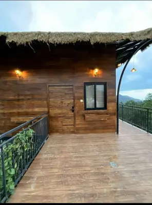 a wooden house with a thatched roof and a deck at Jalsa Bali, Kakkadampoyil, Calicut in Kakkadampoyil