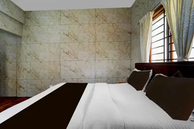 a bedroom with a white bed and a window at Hotel O Gandhipuram Central Bus Stand in Coimbatore
