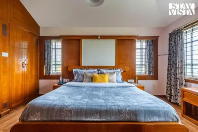 a bedroom with a large bed with a wooden headboard at The Secret Glen by VEO - Part of StayVista with BBQ & Bonfire in Ooty