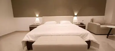 a bedroom with a large white bed and a chair at The Palazzo Chakolas in Trichūr
