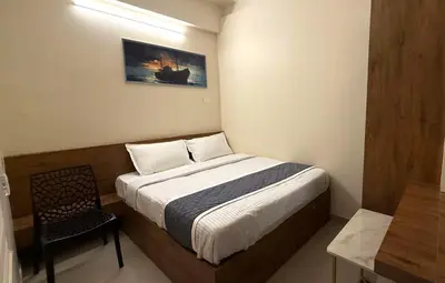 a small bedroom with a bed and a chair at Haaz Grande Kunnamangalam in Kunnamangalam