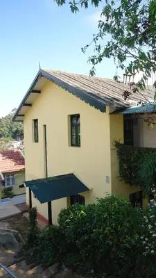 a white house with a blue roof and a building at Glenwood in Coonoor