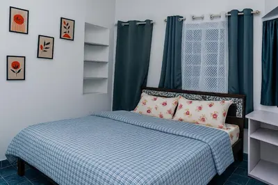 a bedroom with a bed with a blue and white comforter at Pleasant Heights Homestay in Coonoor