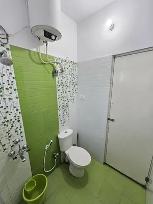 a bathroom with a toilet and a shower with green tiles at Sait's Westhill View Resort in Ooty