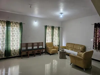 a living room with couches and chairs and windows at Sait's Westhill View Resort in Ooty