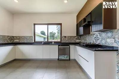 a kitchen with white cabinets and a window at Stayvista at Serenova with big pvt pool and lawn - Your Luxury escape awaits ! in Madikeri