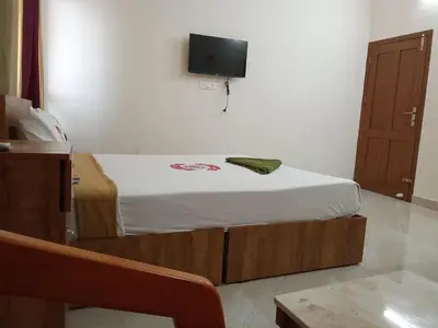 a bedroom with a bed with a tv on the wall at Benzy Tourist Home in Ponnāni
