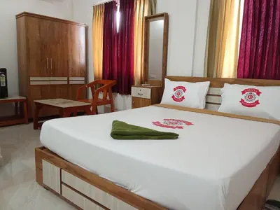 a bedroom with a large white bed with a green towel on it at Benzy Tourist Home in Ponnāni
