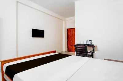 a bedroom with a white bed and a desk at Hotel O Coimbatore Brookefields Mall in Coimbatore