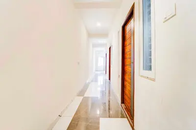 a hallway with white walls and a wooden door at Hotel O Coimbatore Brookefields Mall in Coimbatore