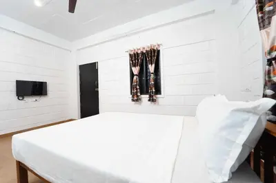 a white room with a bed and baseball bats at Hotel O Coimbatore Brookefields Mall in Coimbatore