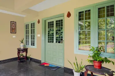 a room with a door and two windows and a table at Hotel O Chalakkudy River Annamanada Svasthya Retreat in Māla