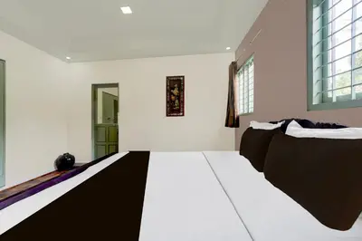a room with two beds and a window at Hotel O Chalakkudy River Annamanada Svasthya Retreat in Māla