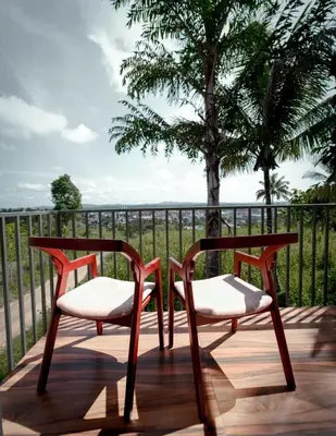 two chairs sitting on a deck with a tree at Revoura Heights Apartments in Sultan Bathery