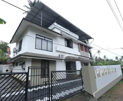a white house with a black fence in front of it at Tranquil Rest House in Trichūr