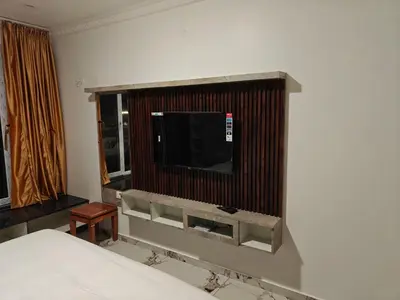 a room with a bed and a tv on a wall at The Ooty Suites in Ooty