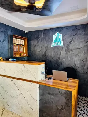 a reception desk with a laptop on a wall at Marvee Luxus Stay in Coimbatore