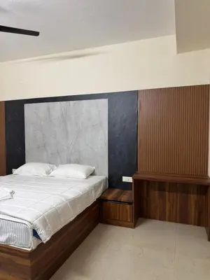 a bedroom with a large bed with a wooden headboard at Marvee Luxus Stay in Coimbatore