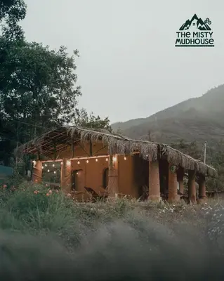 a small building with lights on it in a field at The Misty Mudhouse in Marayoor