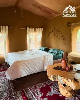 a bedroom with two beds and a table in it at The Misty Mudhouse in Marayoor