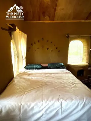 a bedroom with a white bed with two pillows at The Misty Mudhouse in Marayoor