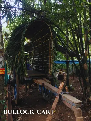 a wheelbarrow with a bench in a forest at Nilambu Homestay in Nilambūr
