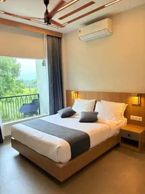 a bedroom with a large bed and a balcony at Cozycaza resort in Padinjarathara