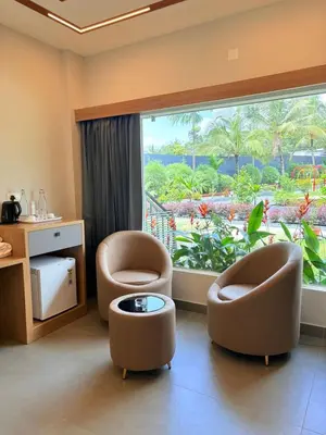 a living room with two chairs and a large window at Cozycaza resort in Padinjarathara