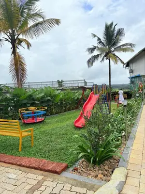 a playground with a slide in a park with palm trees at Cozycaza resort in Padinjarathara