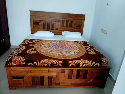 a bed in a bedroom with a wooden headboard at Staycation Homestay in Ernakulam
