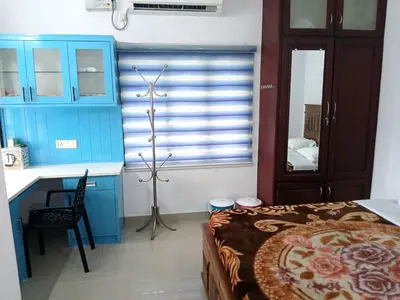a bedroom with blue cabinets and a bed and a desk at Staycation Homestay in Ernakulam