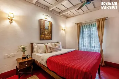 a bedroom with a bed with a red blanket and a window at The Fig Tree Villa by VEO - Part of StayVista in Madikeri