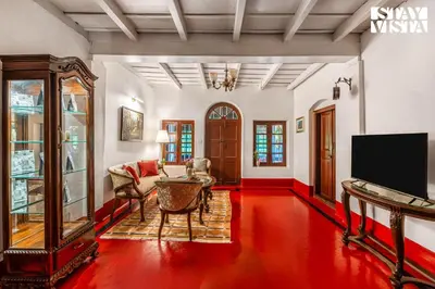 a living room with a red floor and a tv at The Fig Tree Villa by VEO - Part of StayVista in Madikeri