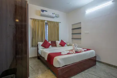 a bedroom with a bed with red pillows at Sree Bharat Apartment in Coimbatore