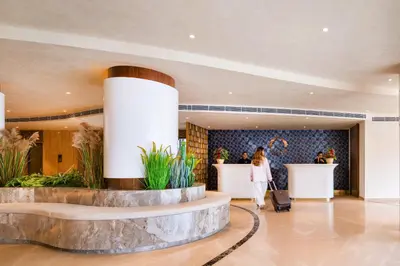 a woman walking through a lobby with her luggage at Oshin Calicut in Kozhikode